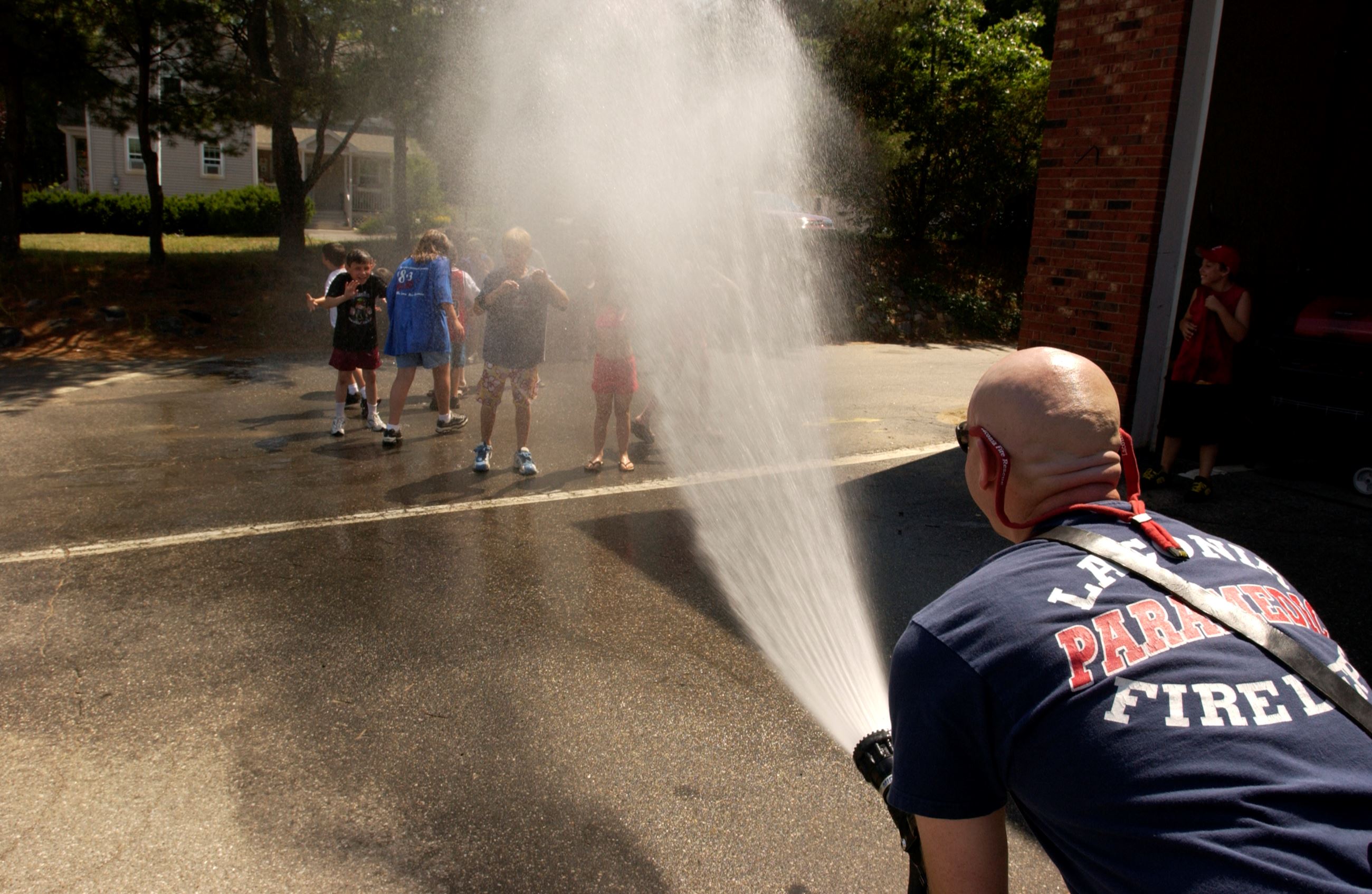 Kids getting sprayed with a fire hose on a hot day